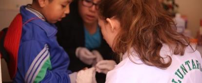 A high school student takes a child's blood sugar measure on our medical internship in Peru
