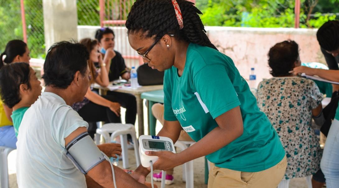 During an outreach, a student takes the blood pressure of a patient during her Public Health internship in the Philippines.