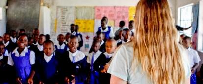Students stand and listen to the Projects Abroad volunteer teaching them in Kenya