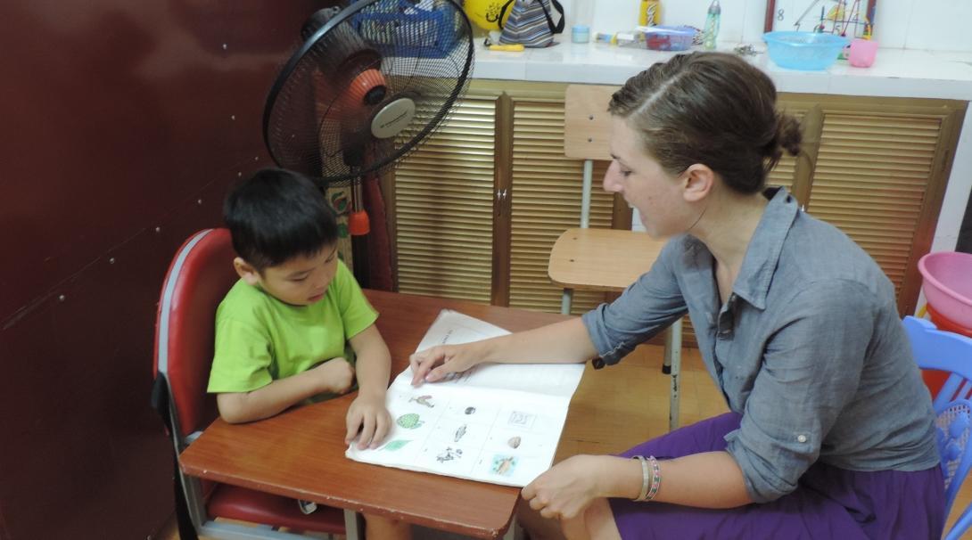 A local child looks at pictures with an Occupational Therapy intern in Vietnam.
