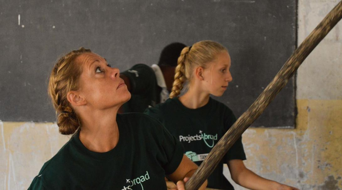 A mother and daughter volunteering overseas together help paint a classroom in Tanzania, Africa. 