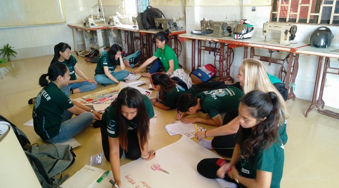 Interns from Projects Abroad can be seen in a classroom making posters to promote nutrition information during their public health internship in Cambodia.