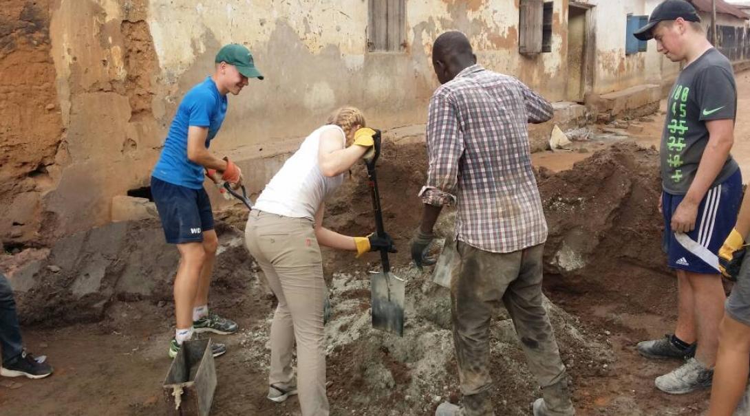A group doing building volunteer work in Africa work with local builders to construct toilets. 