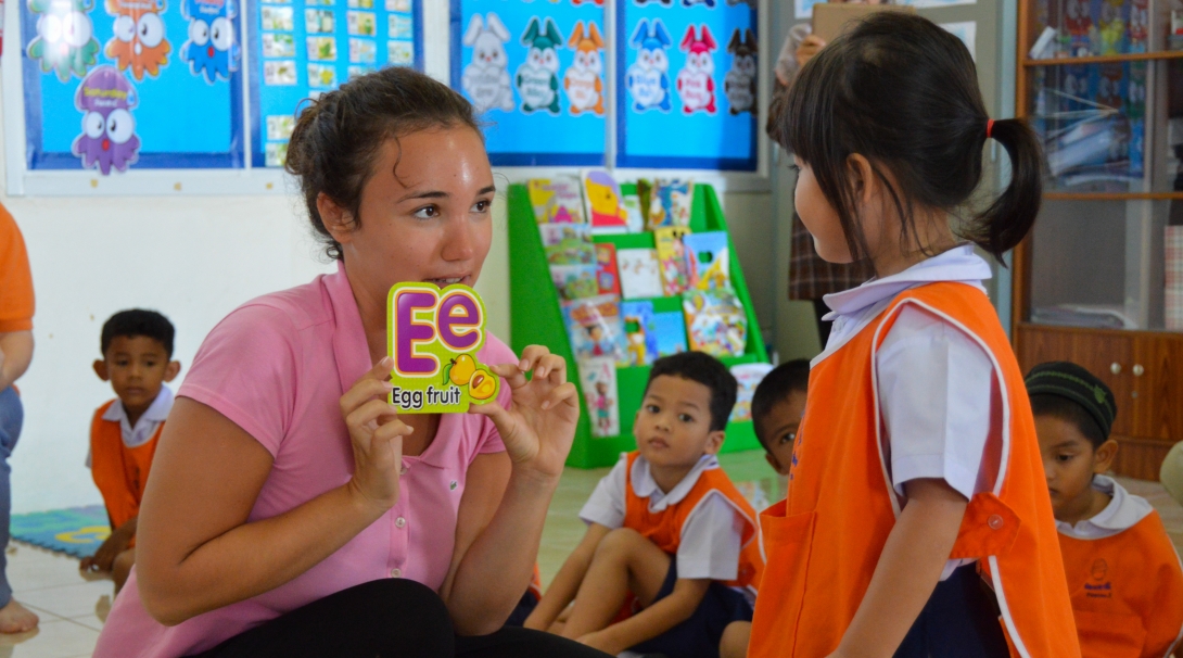 A volunteer teaches the alphabet to children at her Projects Abroad placement where no experience is needed to volunteer overseas.