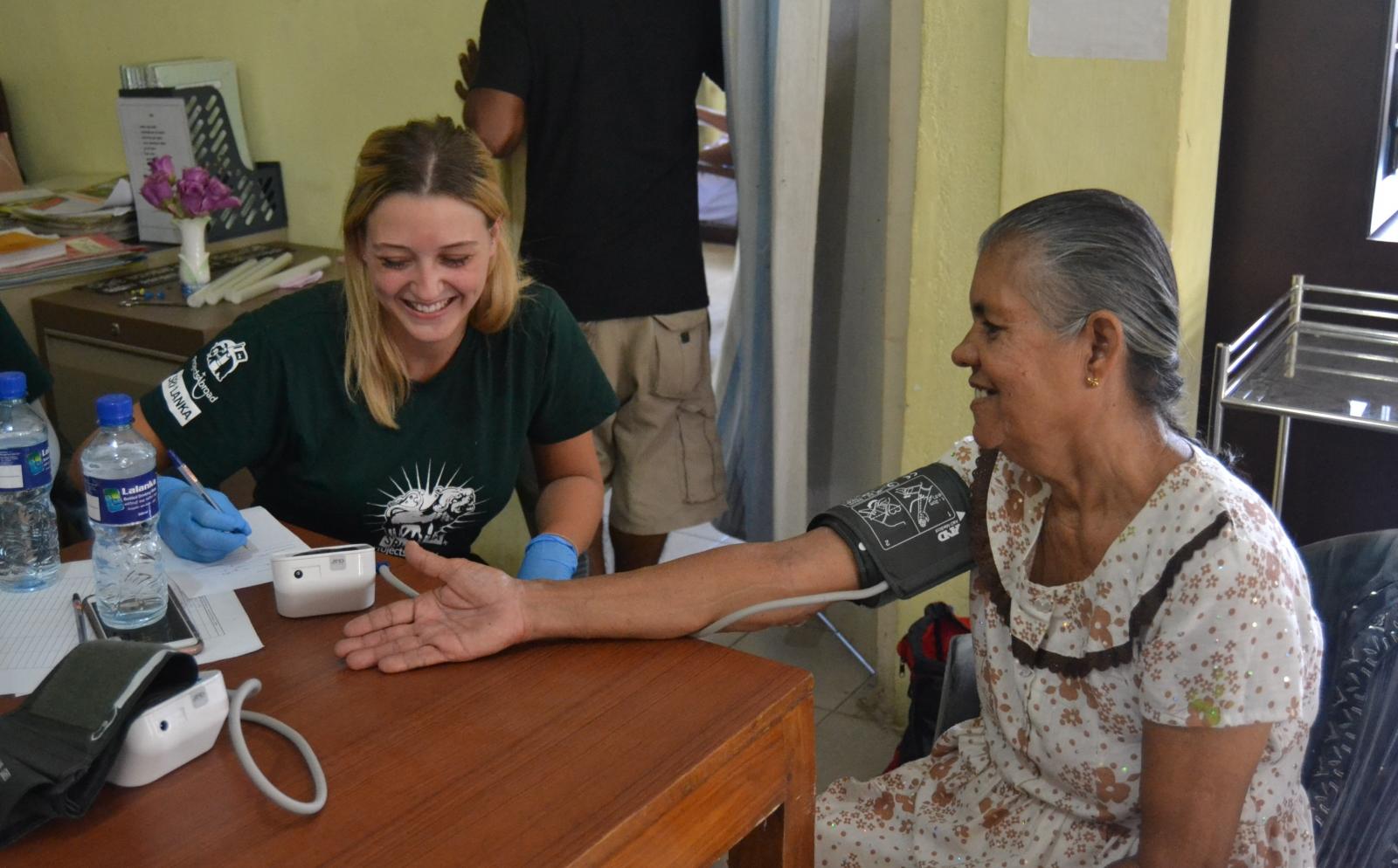 A volunteer on an alternative project to Doctors without Borders takes a patient's blood pressure reading