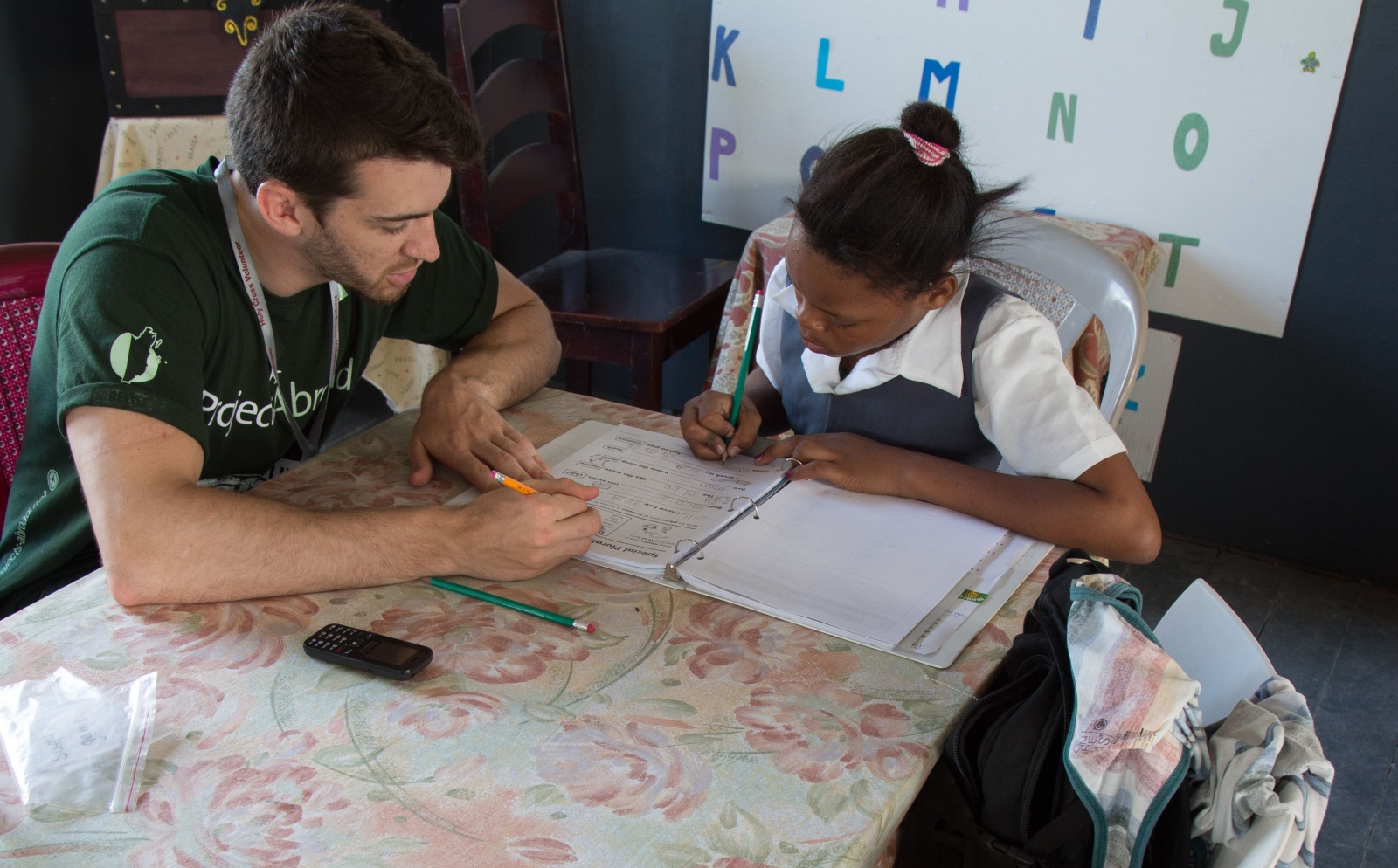 A voluntourist help a child with her reading and writing skills at a school in Belize. 