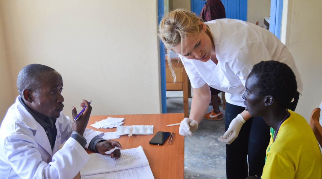 A recent graduate interning abroad assists a local doctor during a medical outreach in Kenya. 