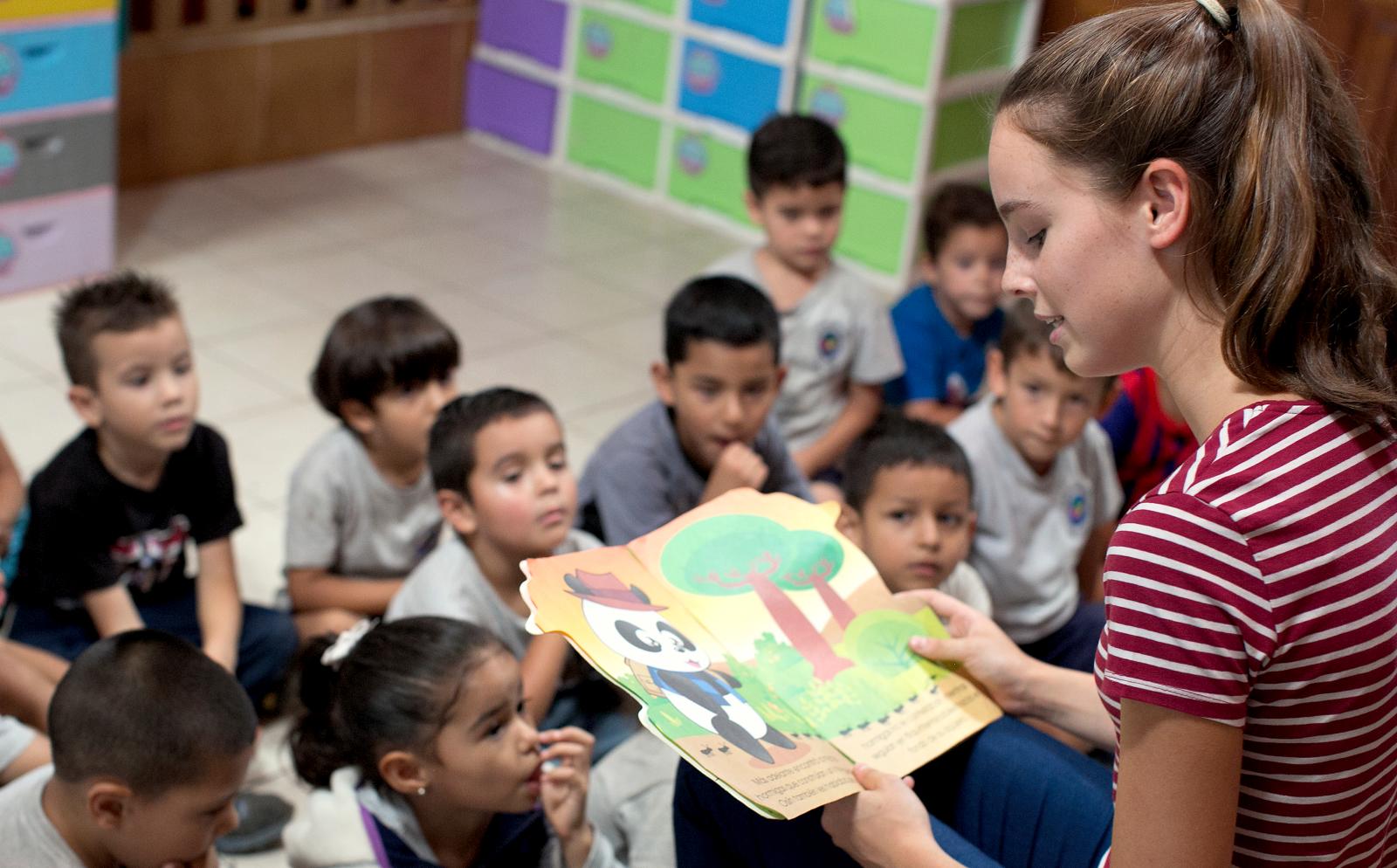 Childcare and Conservation volunteer reads a story to the children in her class