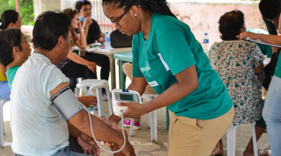 A Public Health volunteer takes the blood pressure of a local man during a medical outreach 
