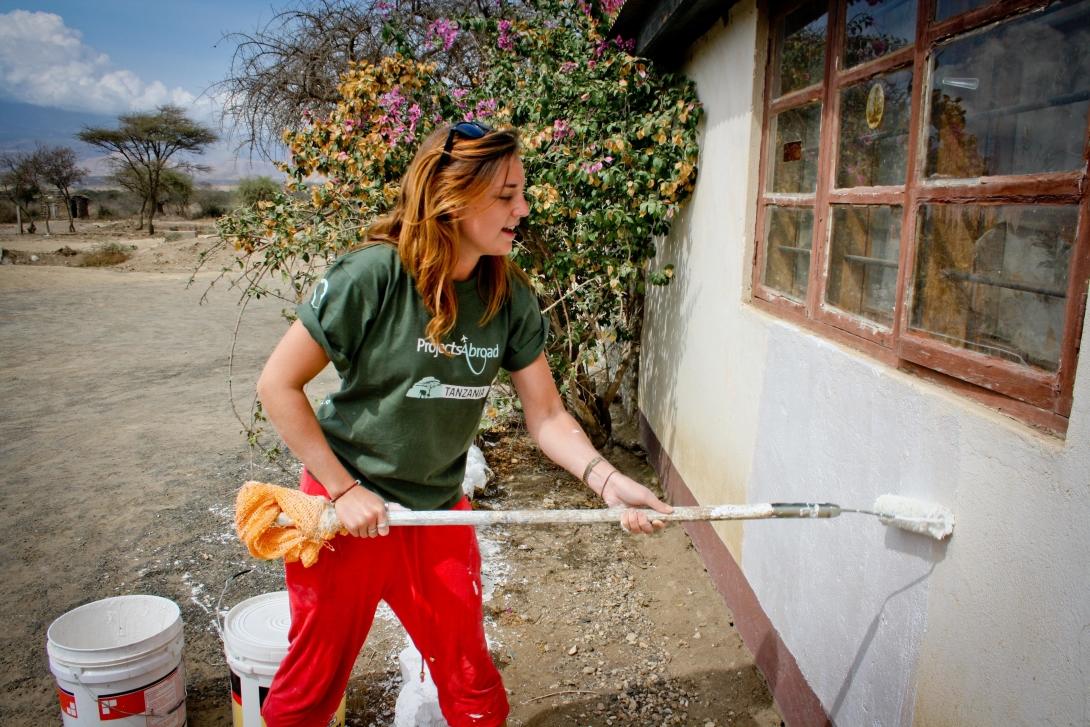 A Building volunteers adds a coat of paint to a newly built classroom in Tanzania