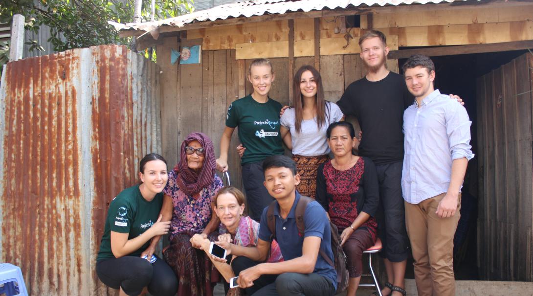 Volunteers take a group photo with a local family during their time abroad