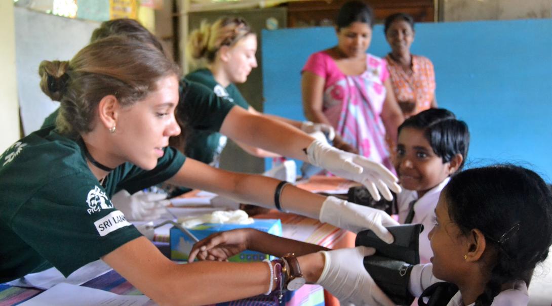 Healthcare volunteers checking the blood pressure of children in Sri Lanka during their time abroad 