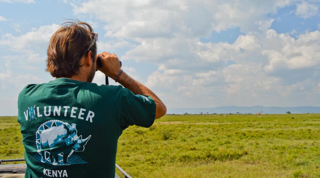 A conservation volunteer in Kenya searches for wildlife