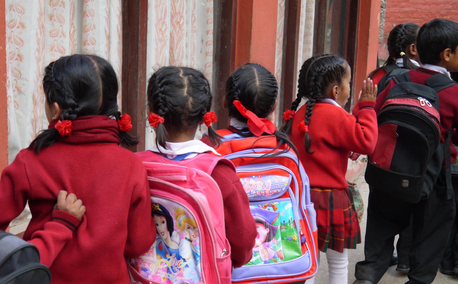Children line up with their backpacks outside their classroom in Nepal