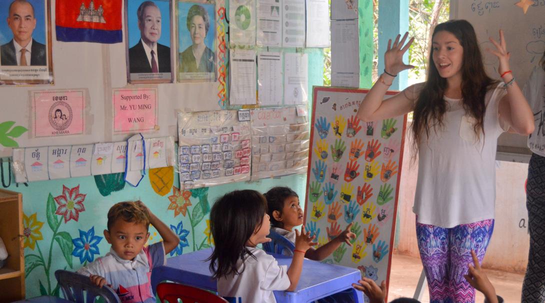 A High School Special Volunteer is teaching English words to the local children at the care & community placement during her volunteering trip in Cambodia.