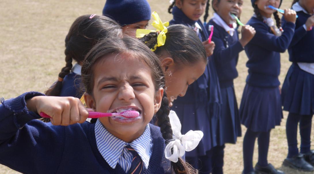 A young girl brushes her teeth during a hygiene workshop in Nepal