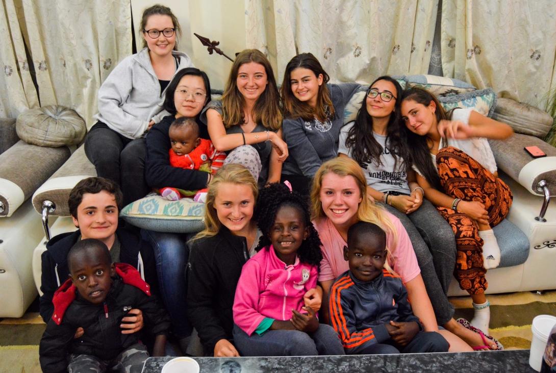 High School Special volunteers sitting in the living room with their host family’s children in Kenya