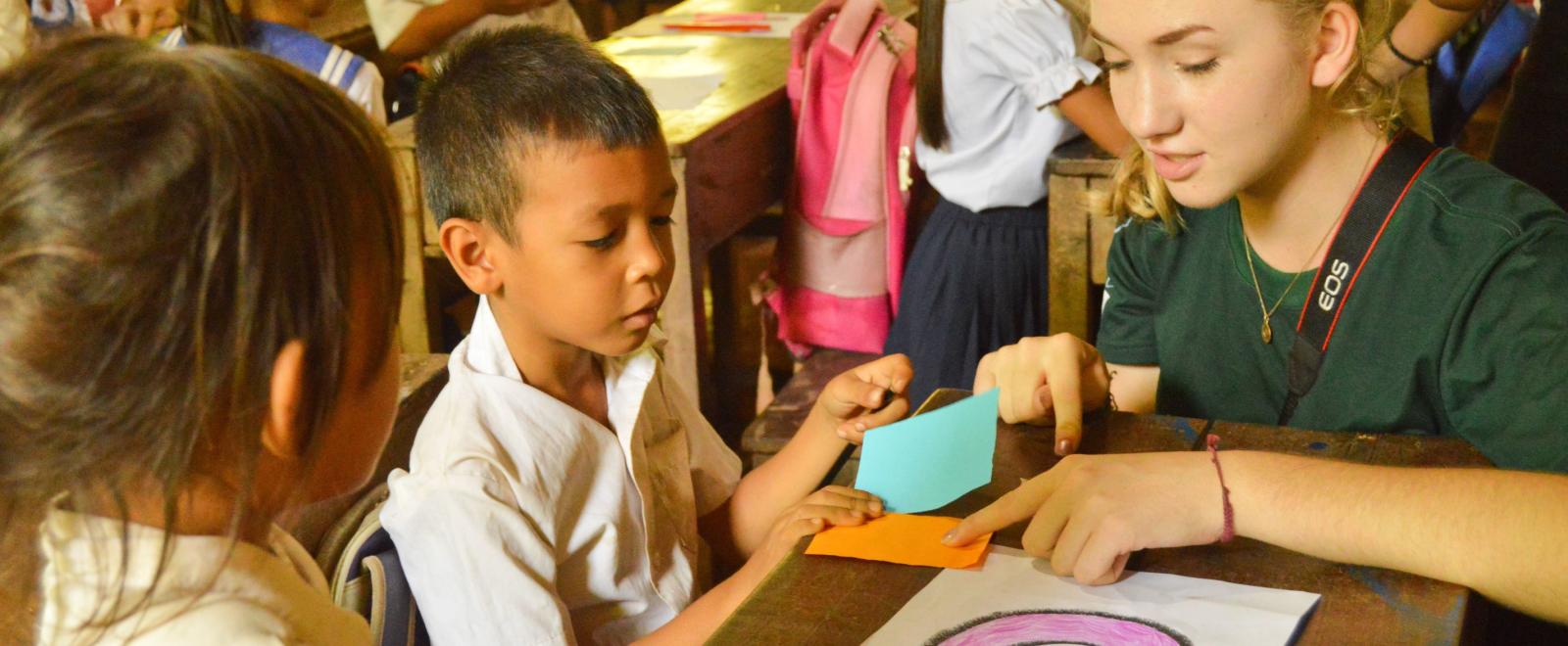 Childcare volunteer teaches a young boy different colours during school in Cambodia