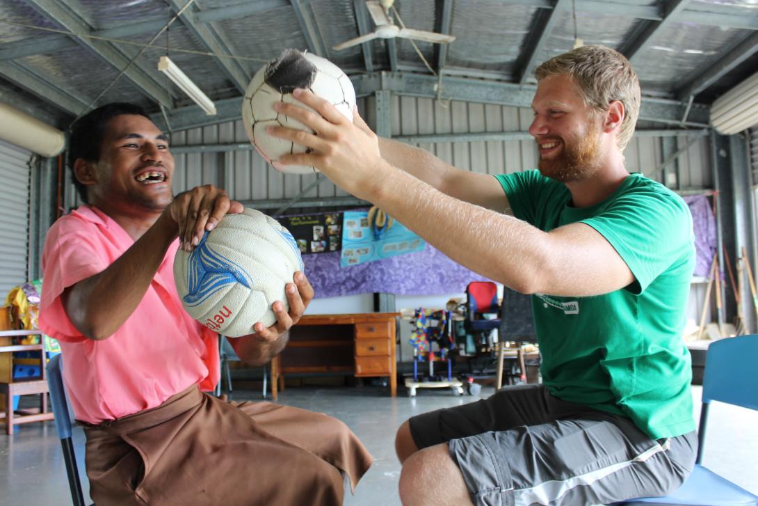 A care volunteer making a disabled man smile playing ball games