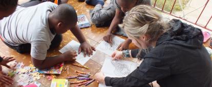 A Projects Abroad volunteer on her Spring Break Project coloring books with the children at her Childcare placement in Jamaica