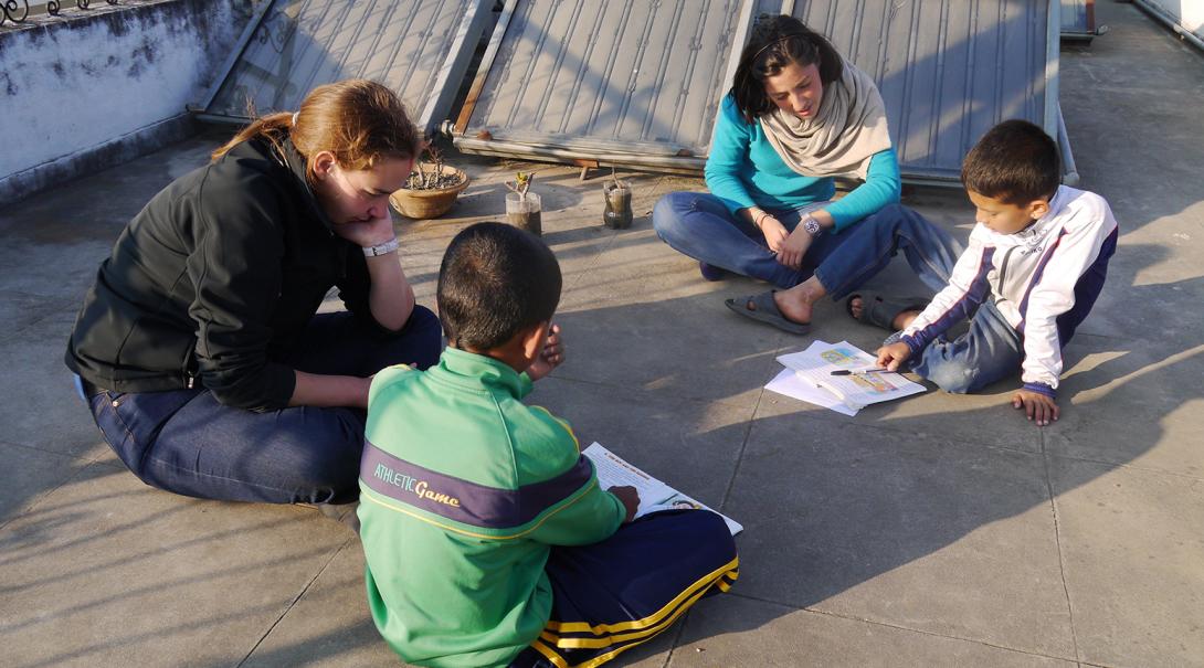 Projects Abroad volunteer help their students with their English reading in Nepal