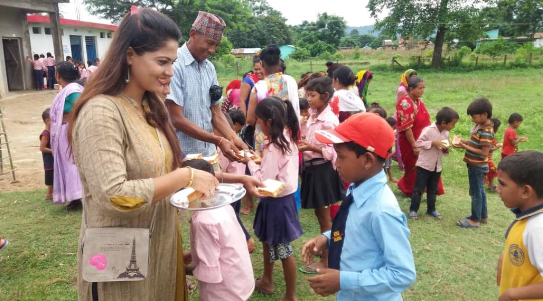 Local staff and volunteers hand out meals to the students for lunch in Nepal