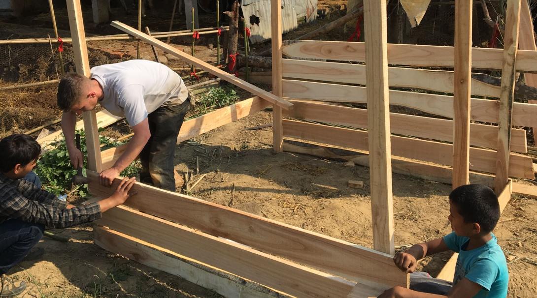 Volunteers help build a chicken coop at a school in Nepal.