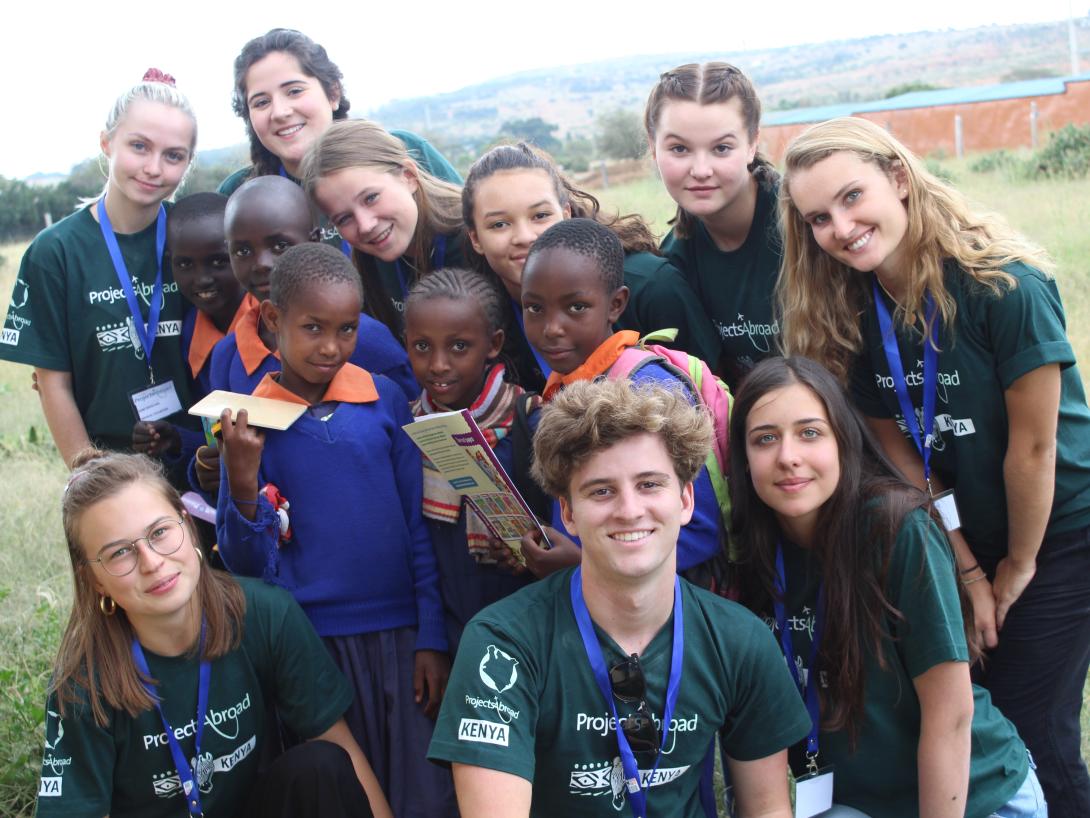 Teens take a photo with Kenyan children after a medical outreach at a school as part of a service learning trip for high school students