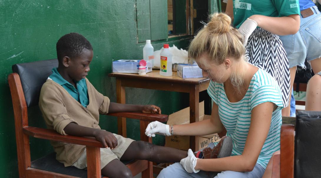 A Public Health volunteer treats a boy´s injury in a welfare clinic during her internship with Projects Abroad in Ghana.
