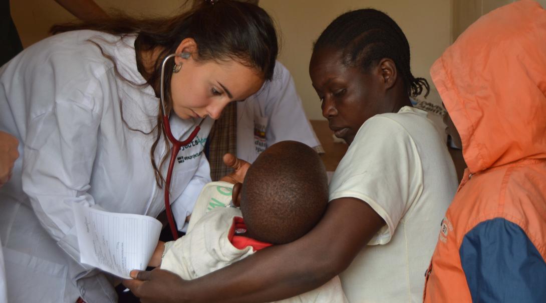 A Projects Abroad volunteer doing a midwifery internship in Ghana checks a baby's stomach.