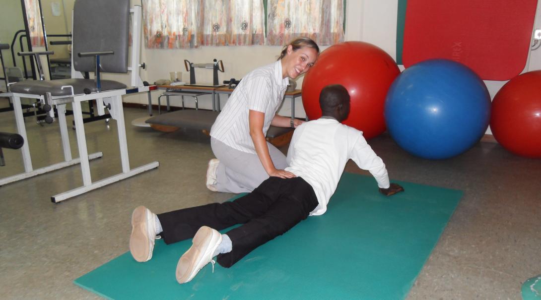 A Projects Abroad volunteer doing a physiotherapy internship in Ghana helps an adult with his therapy routine.