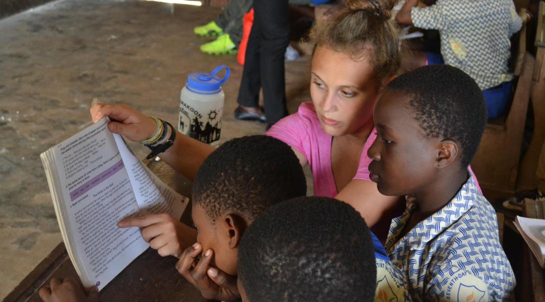 A Projects Abroad volunteer explains a text to some students in Ghana during her teaching English internship.