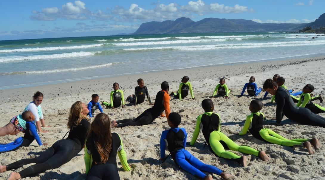 Projects Abroad volunteers stretch their muscles before starting their Surfing gap year programme in South Africa