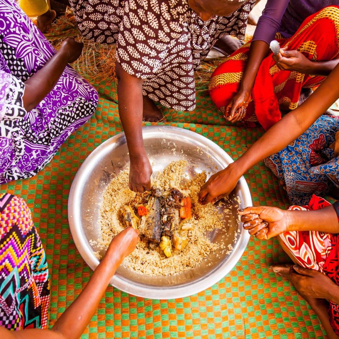 Tanzanian women eat out of a communal bowl of food during lunch time.