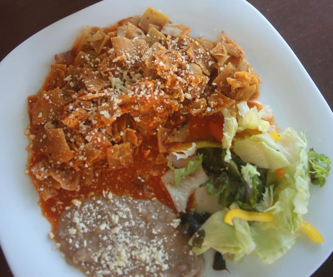 A traditional breakfast of red chilaquiles and beans in Mexico. 