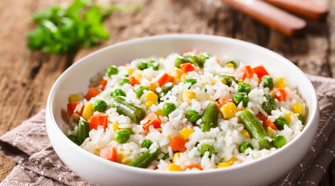 A bowl of cooked white rice with colourful vegetables