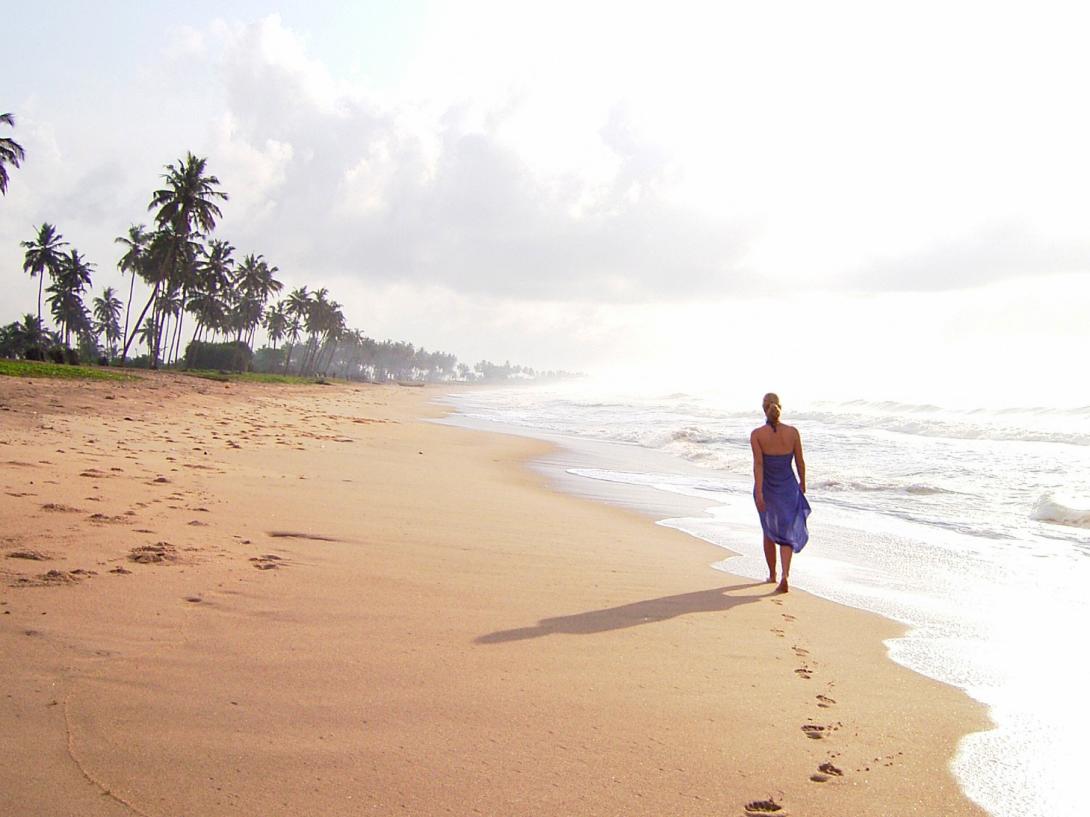 On a hot day in Ghana, a woman strolls on the beach